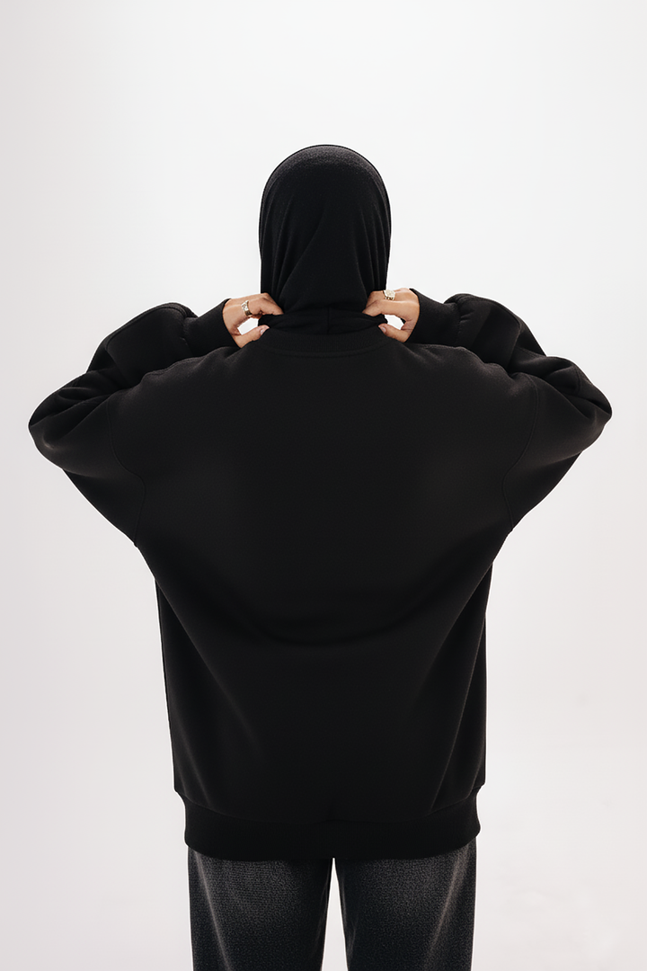 Model wearing Blancka oversized black basic crewneck sweatshirt — minimalist winter collection. 