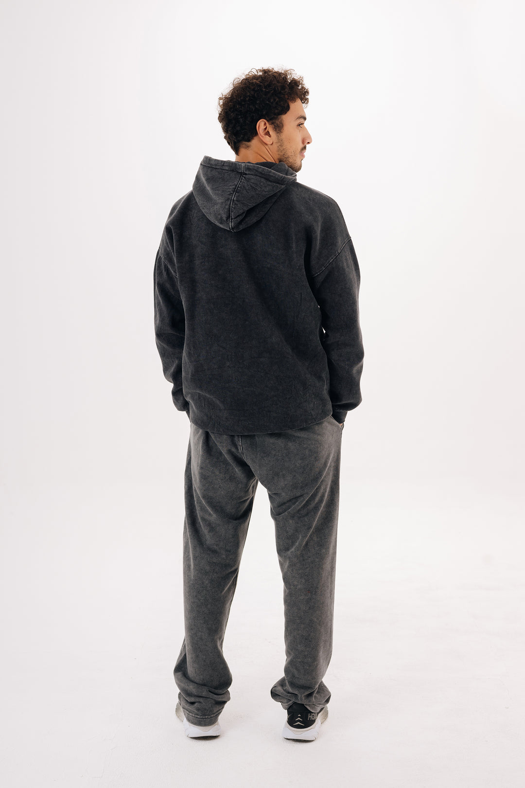 Back view of charcoal black washed oversized hoodie on male model — white studio background
