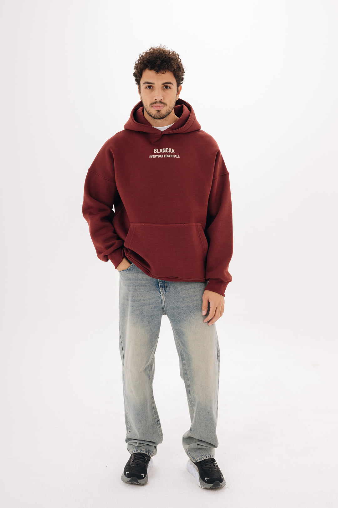 Male model wearing burgundy boxy hoodie with front chest print ? studio background