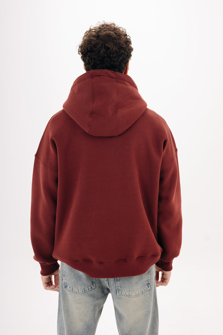 Male model wearing burgundy boxy hoodie with front chest print ? studio background