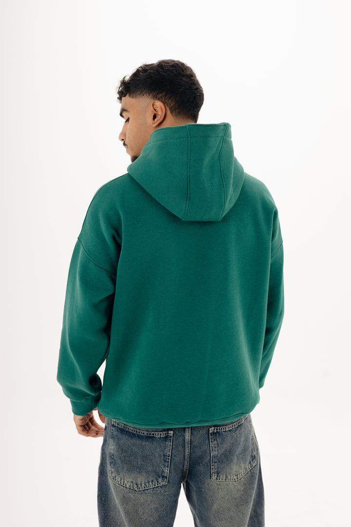Male model wearing green boxy Blancka hoodie with front print ? studio white background