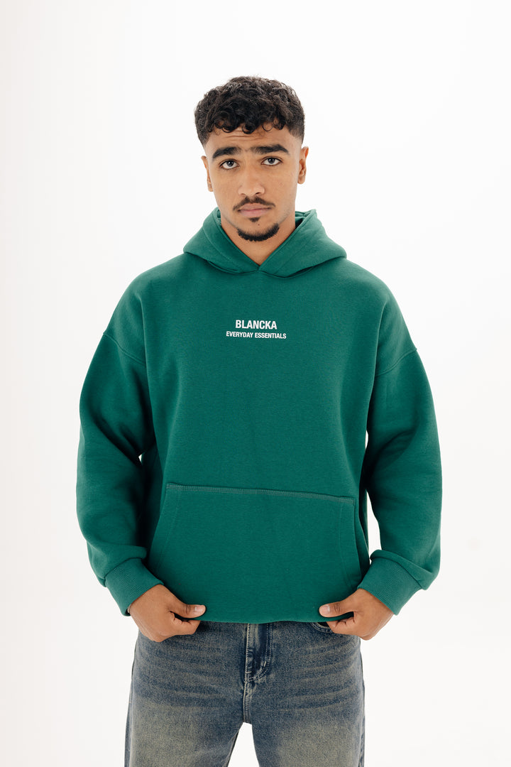 Male model wearing green boxy Blancka hoodie with front print ? studio white background