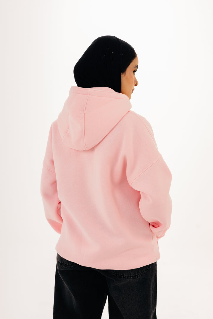 Back view of pink oversized hoodie worn by female model with hijab ? studio white background