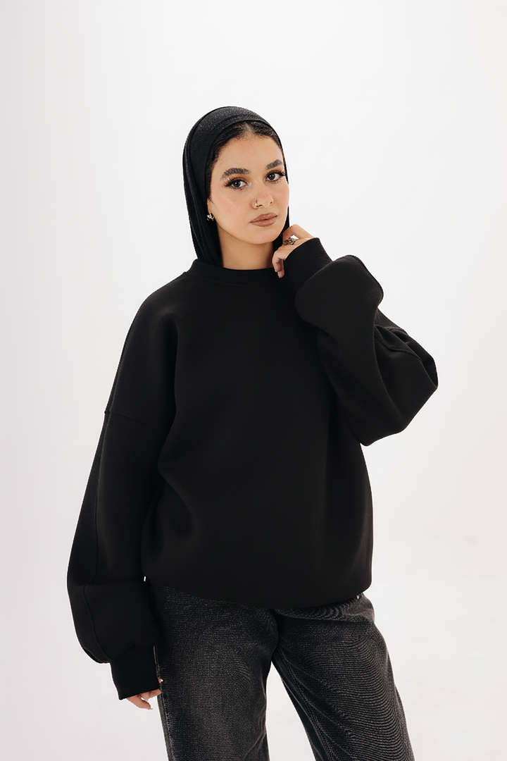Model wearing Blancka oversized black basic crewneck sweatshirt — minimalist winter collection. 