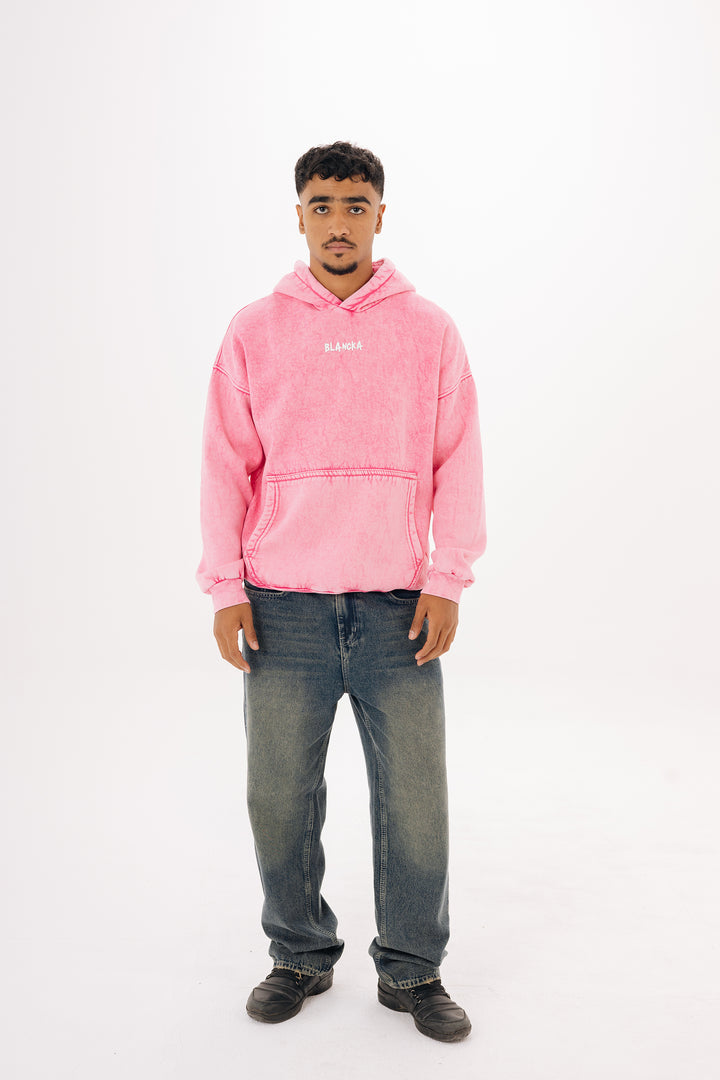 Full outfit — male model wearing pink washed hoodie styled with washed jeans — studio background
